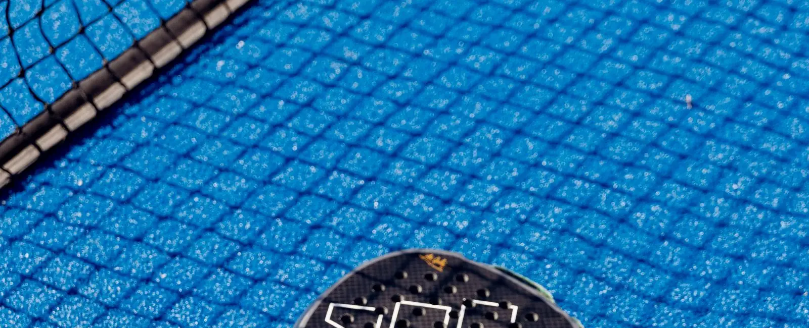 Raquette et balle de padel posées près du filet
